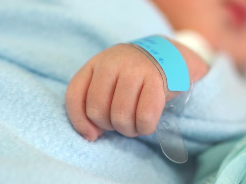 mala rukica novorođene bebe sa narukvicom sa imenom oko ruke